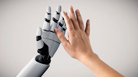 A robotic hand and a human hand high-five each other. 